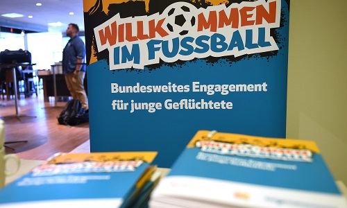 "Willkommen im Fußball"-Banner im Hintergrund und Broschüren im Vordergrund bei einer Veranstaltung der DFL Stiftung zur Vorstellung von Flüchtlingsprojekten des HSV und FC St. Pauli sowie des bundesweiten Integrationsprogramms.