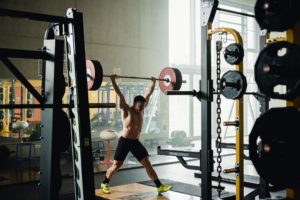 Gewichtheber Max Lang hebt in einem Fitnessstudio eine schwere Langhantel über Kopf.