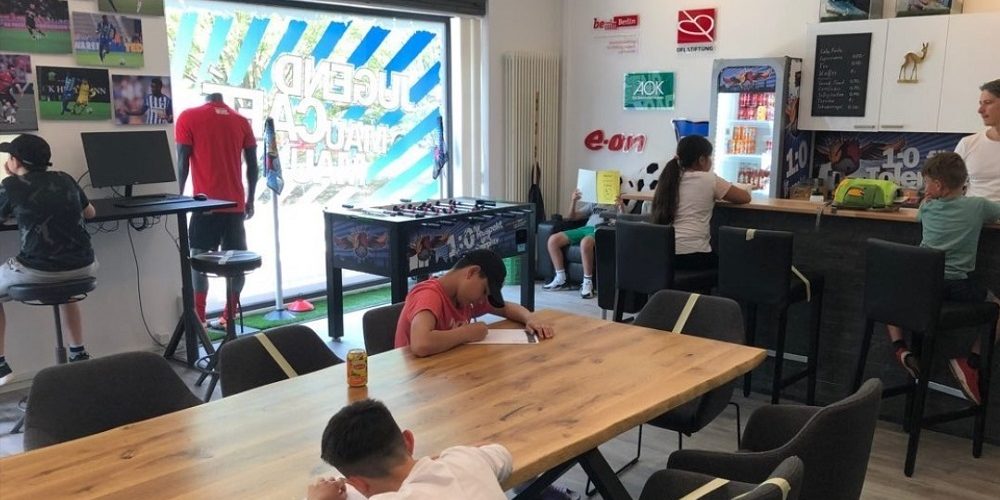 Kinder sitzen im Jugend Café und schreiben und lesen
