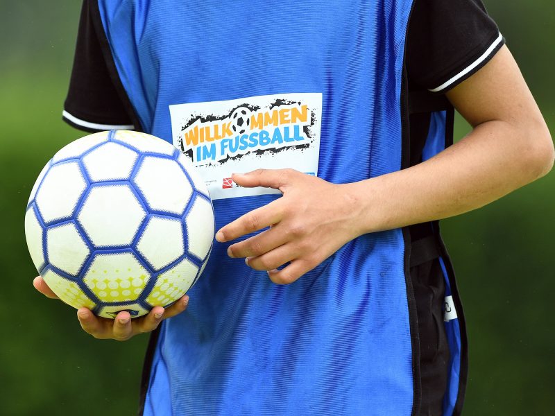 Ein Junge im blauen Trikot hält den Fußball in der rechten Hand