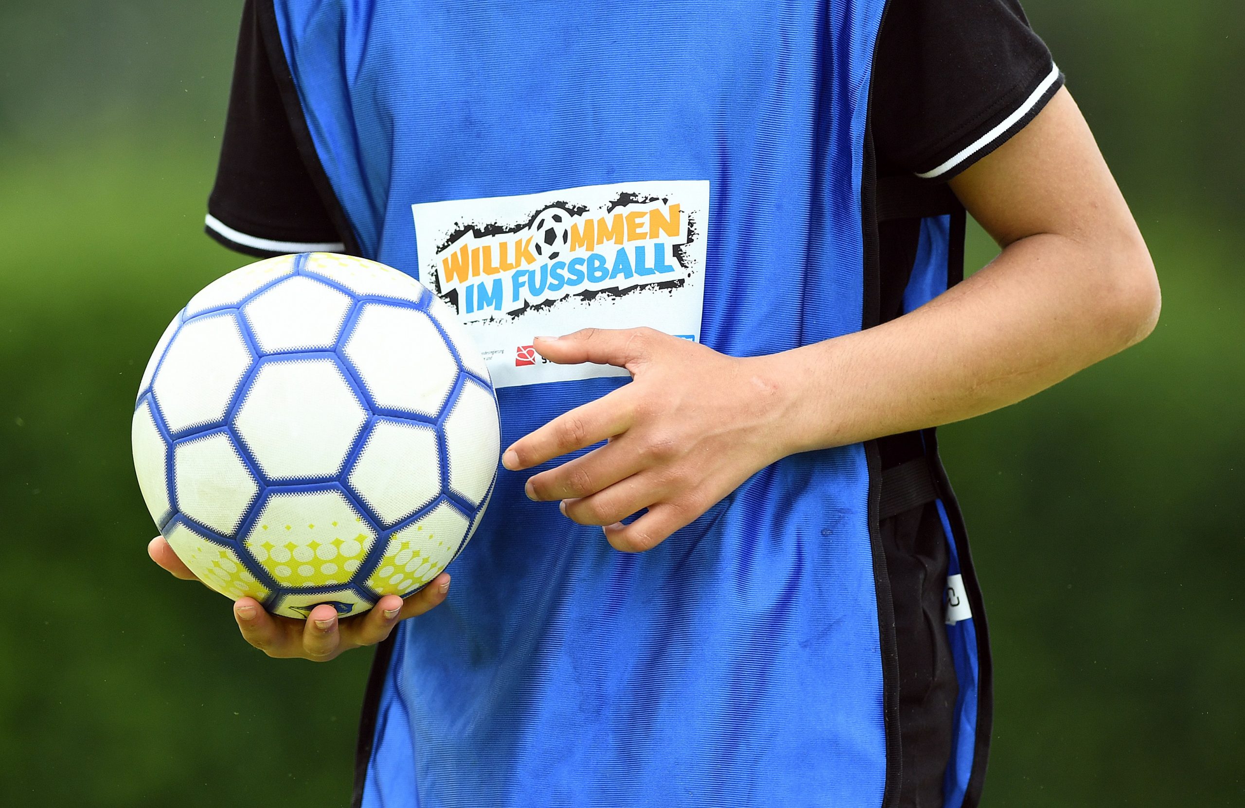 Ein Junge im blauen Trikot hält den Fußball in der rechten Hand