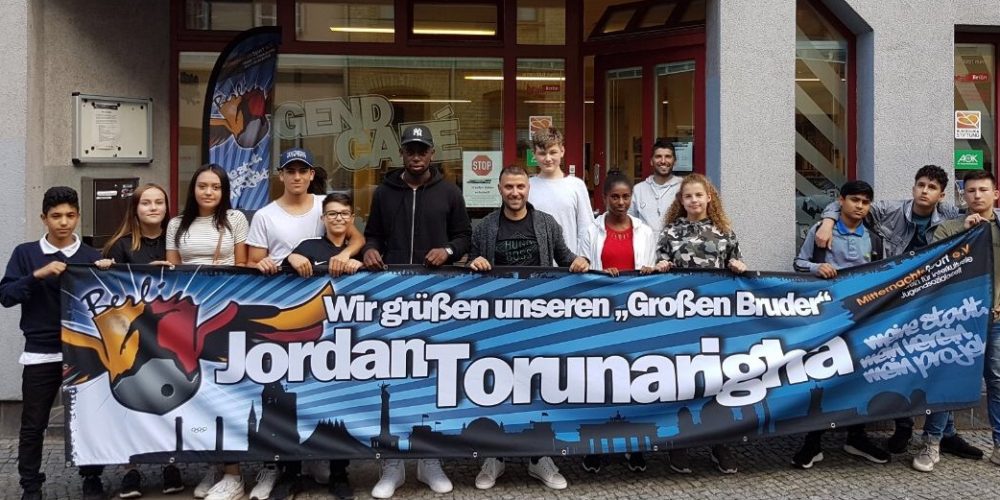 Jugendliche stehen zusammen mit Jordan Torunarigha und Ismail Öner vor dem Jugend Café