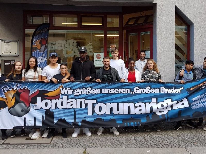 Jugendliche stehen zusammen mit Jordan Torunarigha und Ismail Öner vor dem Jugend Café