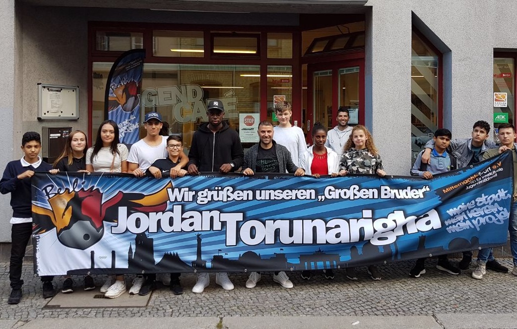 Jugendliche stehen zusammen mit Jordan Torunarigha und Ismail Öner vor dem Jugend Café