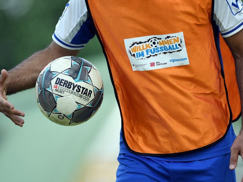 Mann im Trikot mit dem Logo ,,Willkommen im Fußball" spielt mit dem Ball