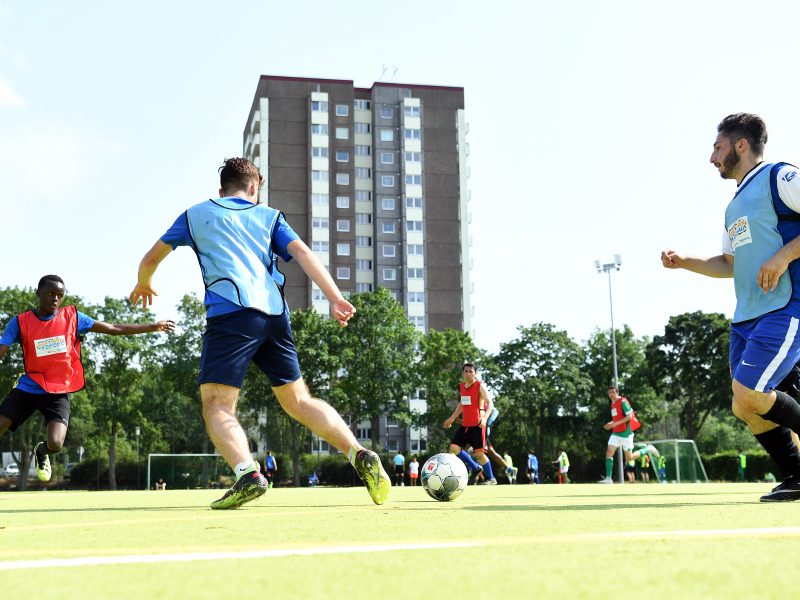 Jungen in blauen und roten Trikots spielen Fußball