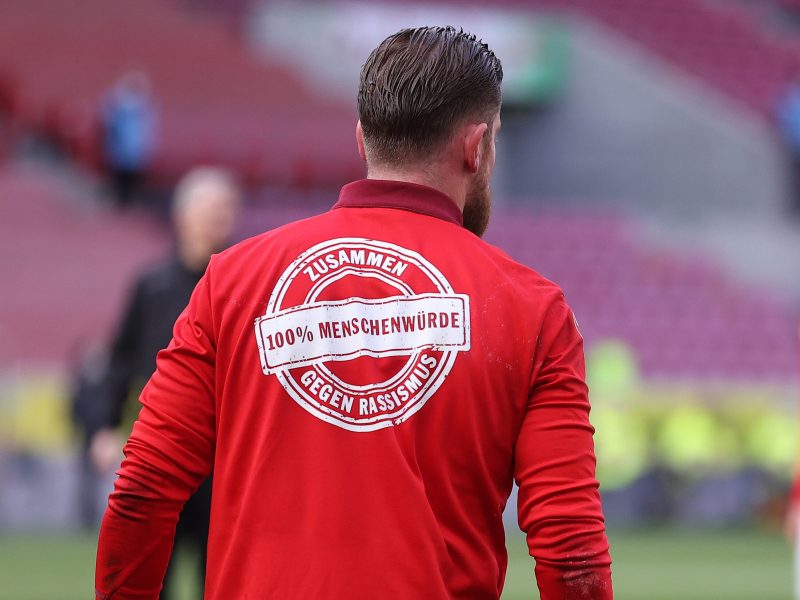 Fußballer im roten Trikot mit dem Logo "Zusammen gegen Rassismus-100% Menschenwürde"