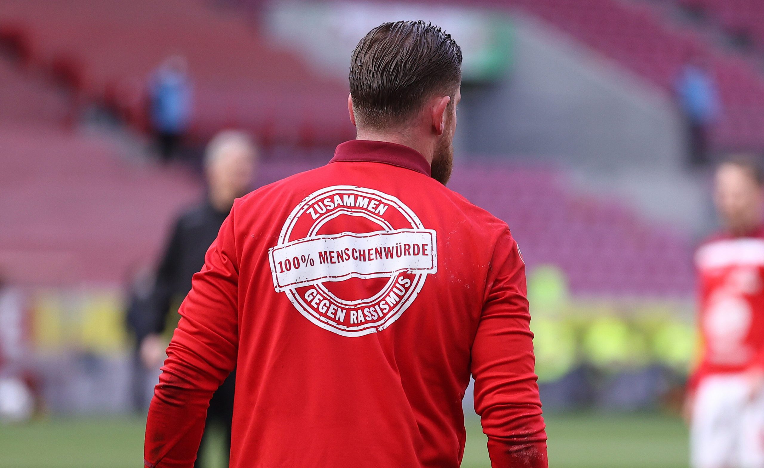 Fußballer im roten Trikot mit dem Logo "Zusammen gegen Rassismus-100% Menschenwürde"