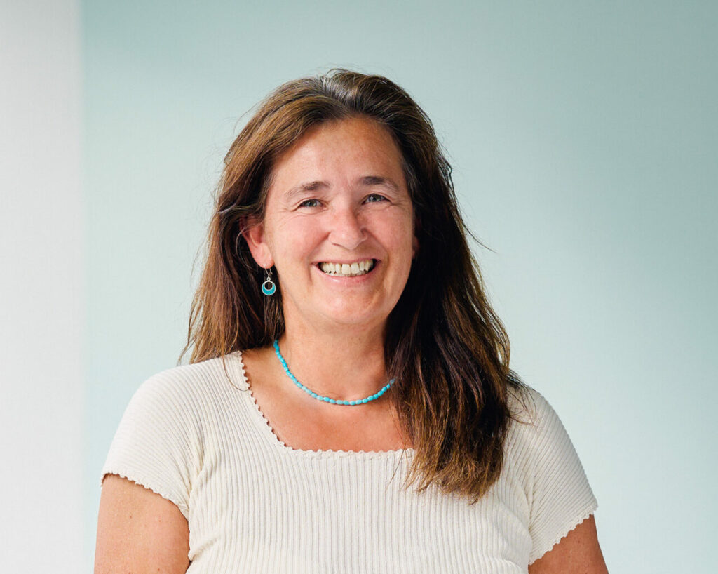 Clarissa Sagerer-Schlockermann, lächelnde Frau mit langen braunen Haaren vor hellem Hintergrund.