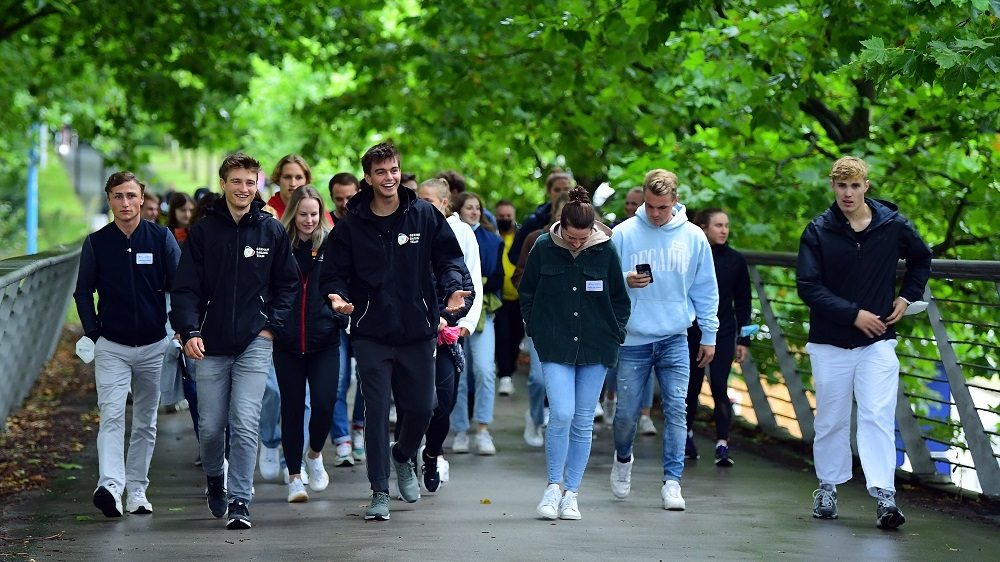 Die Athletinnen und Athleten laufen über die Brücke zum Stadion