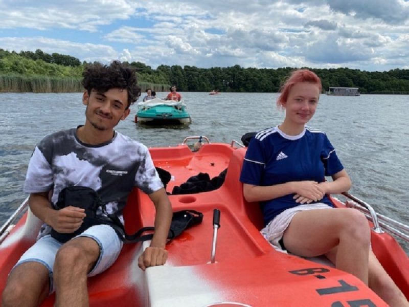 Ein Junge und ein Mädchen sitzen in einem roten Tretboot.