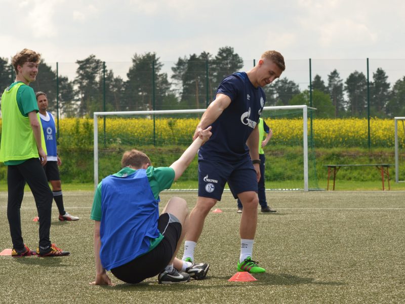 Ein Fußballspieler gibt die Hand seinem Mitspieler und hilft ihm aufzustehen