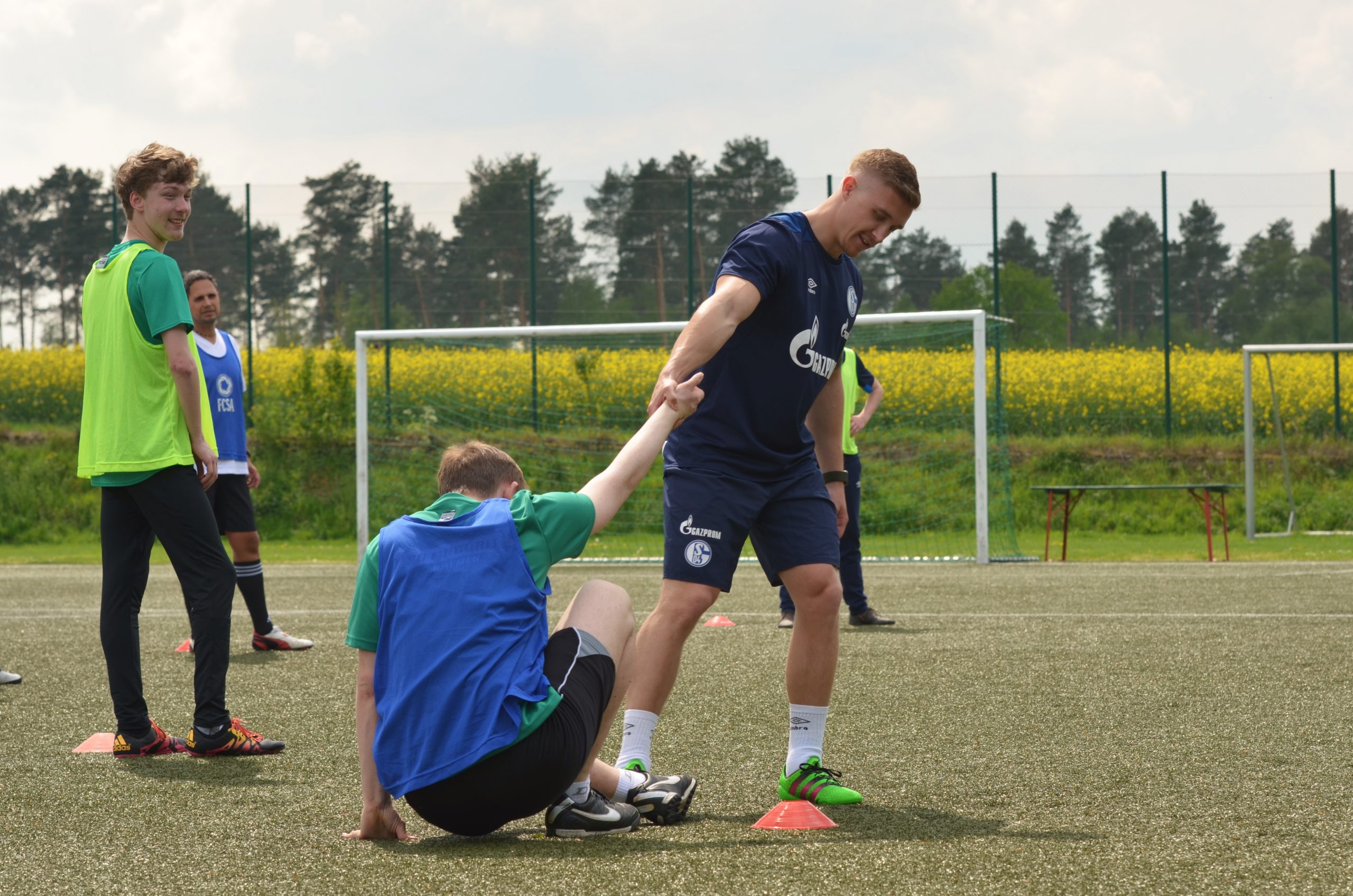 Ein Fußballspieler gibt die Hand seinem Mitspieler und hilft ihm aufzustehen