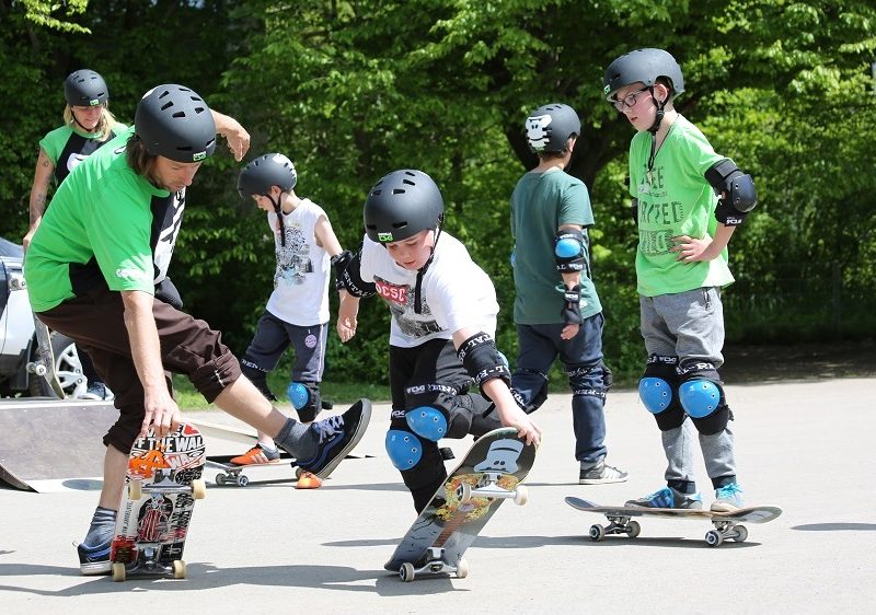 Die Teilnehmenden fahren Skateboards auf dem Spielplatz.