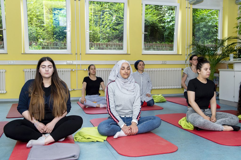 Sechs junge Frauen machen Yoga.