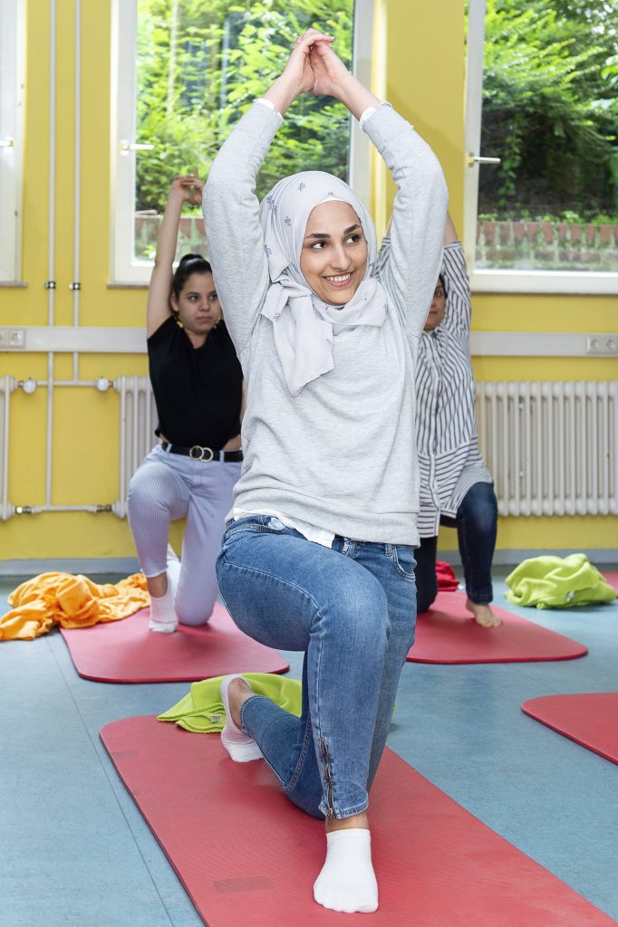 Drei Mädels machen Yoga auf den roten Matten.