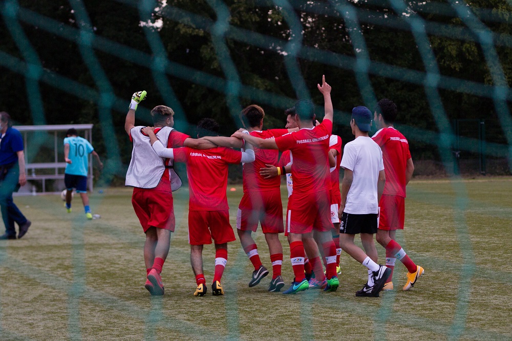 Ein Fußballteam in roten Trikots jubelt und liegt sich in den Armen.