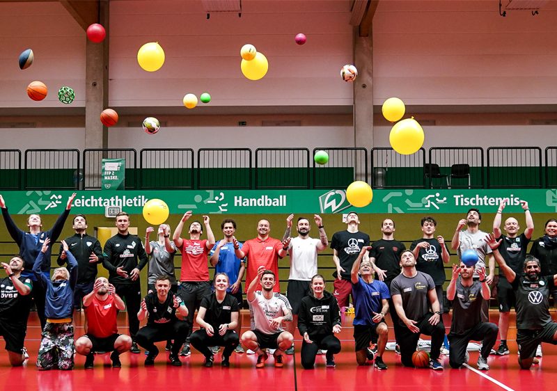 Die Teilnehmenden der Qualifizierungsveranstaltung werfen nach einer Sporteinheit bunte Luftballons in den Turnhallen-Himmel.