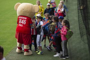 Einige Kinder kommen zum Maskottchen.