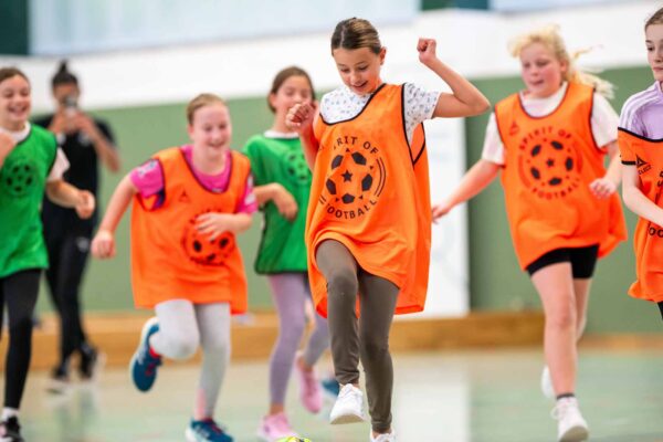 6 Mädchen spielen gemeinsam Fußball und lachen dabei