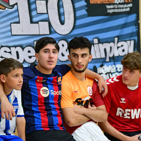 Jugendliche sitzen nebeneinander und haben sich im Arm