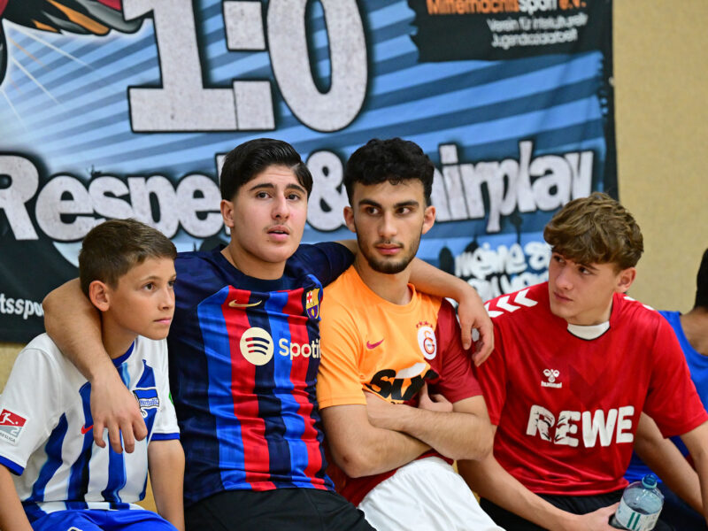 Jugendliche sitzen nebeneinander und haben sich im Arm