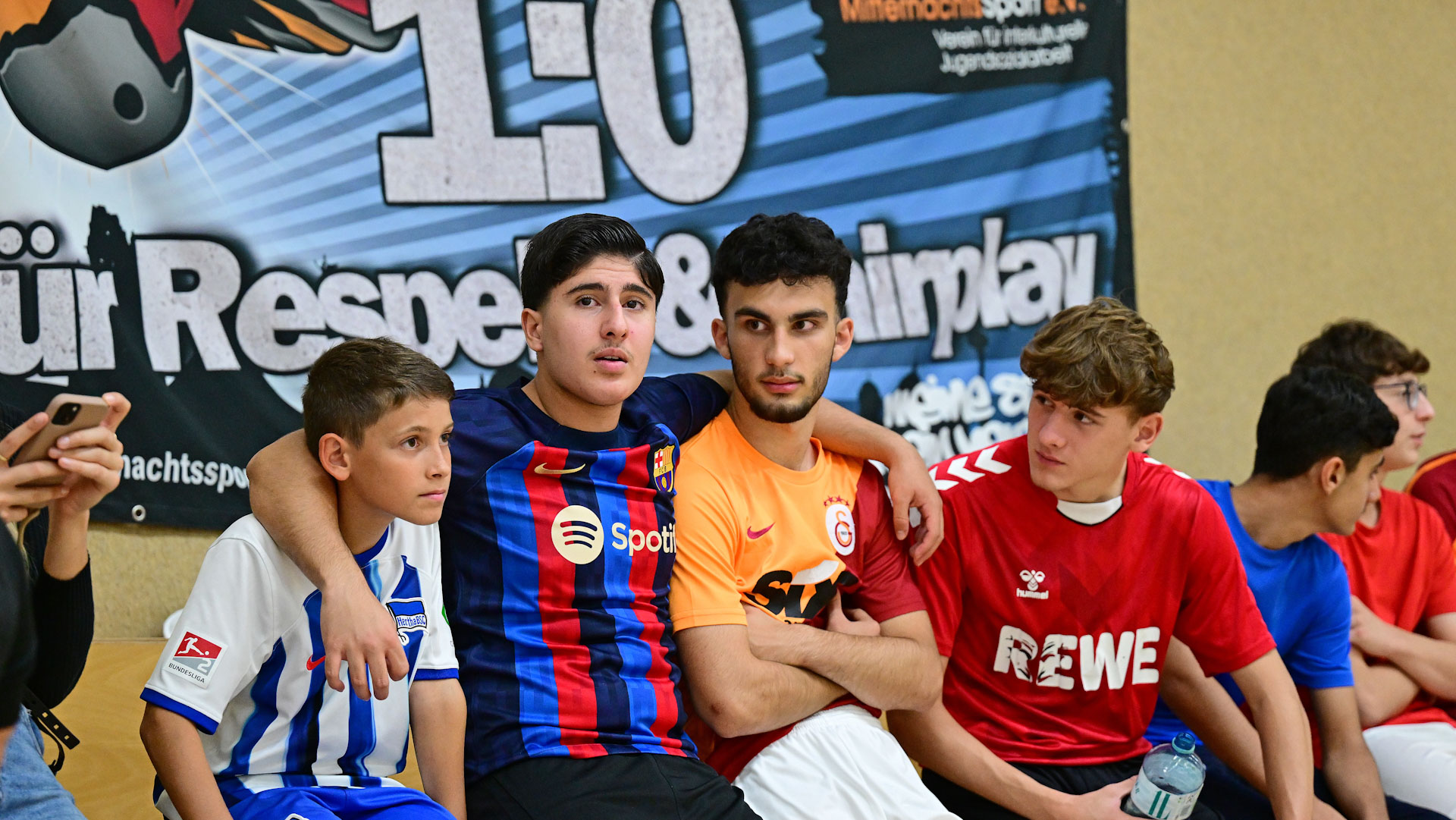 Jugendliche sitzen nebeneinander und haben sich im Arm