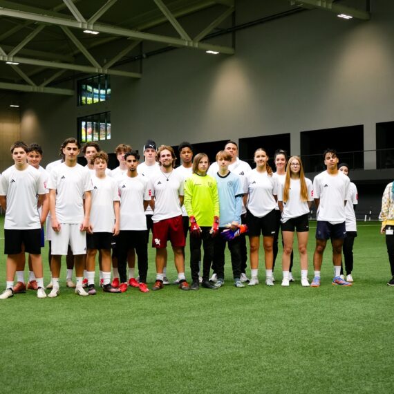 Eine Gruppe junger Menschen steht in Trikots aufgereiht auf einem Fußballplatz