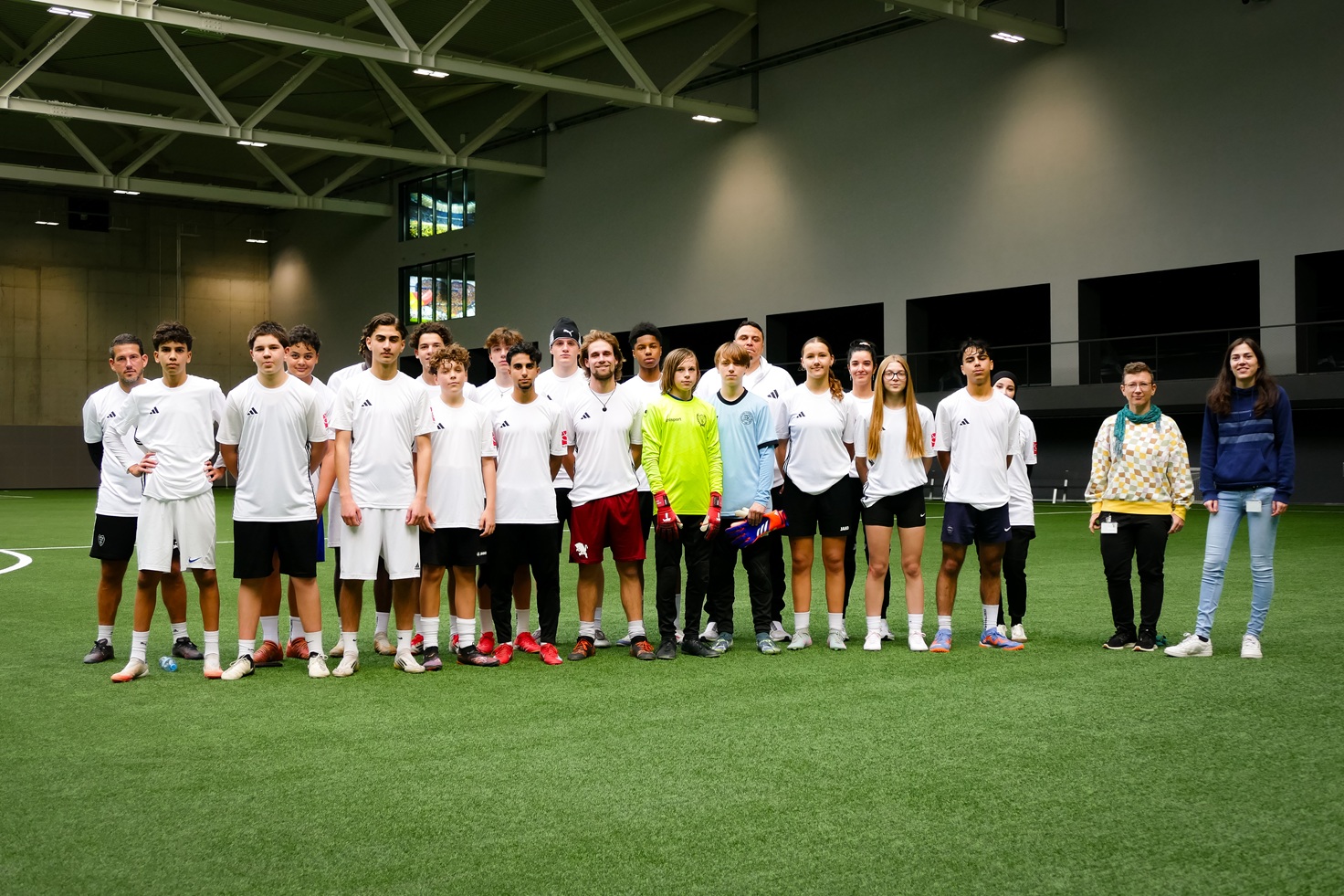 Eine Gruppe junger Menschen steht in Trikots aufgereiht auf einem Fußballplatz