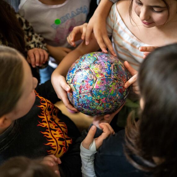 Mädchen stehen rund um einen bunten Ball
