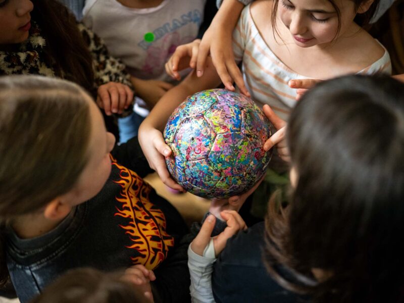 Mädchen stehen rund um einen bunten Ball