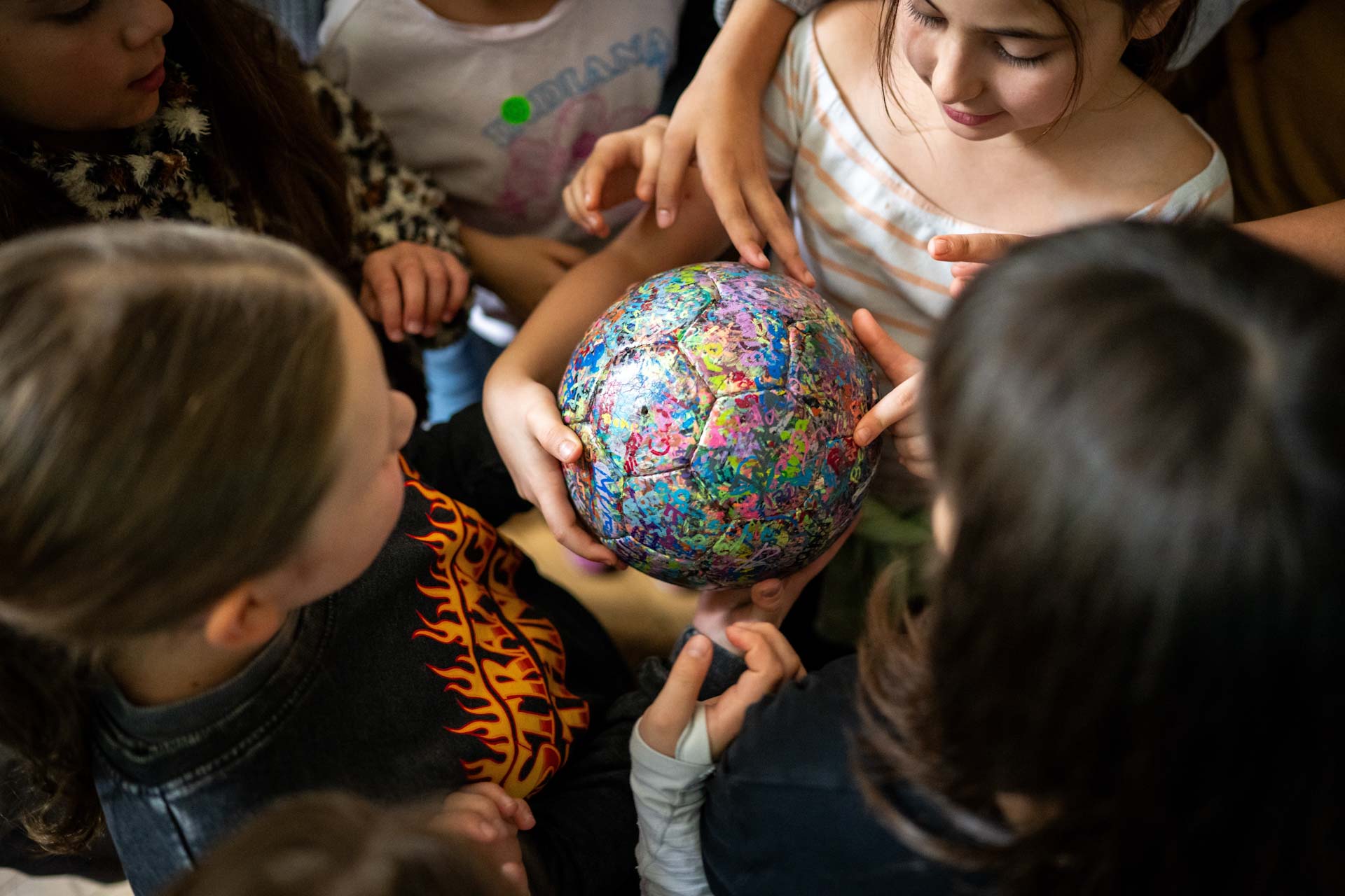 Mädchen stehen rund um einen bunten Ball