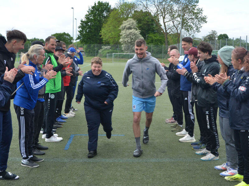 Zwei Menschen laufen lachend durch ein Spalier aus Menschen