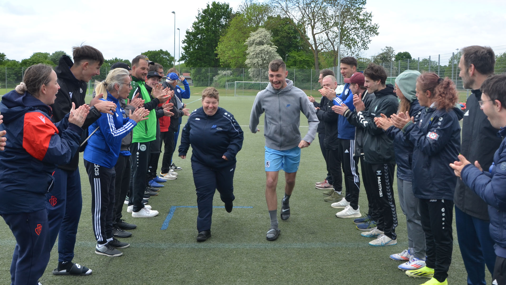 Zwei Menschen laufen lachend durch ein Spalier aus Menschen